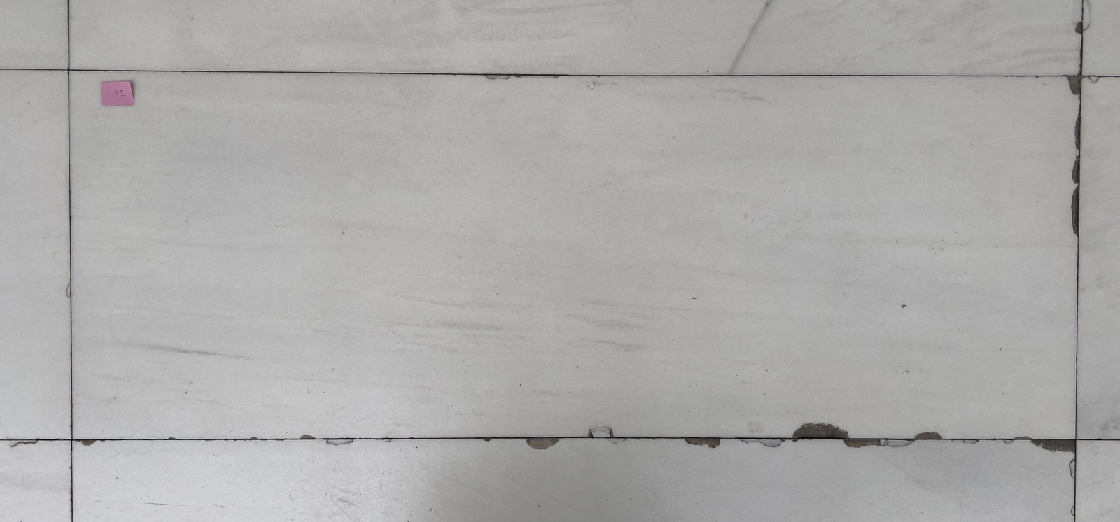 Chipping: Kantenabplatzungen entlang der Fugen auf weißem Naturstein
